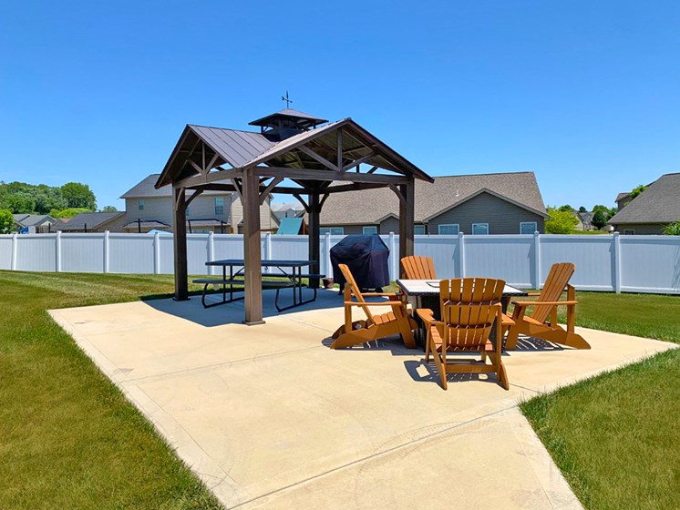 concrete patio with 4 wooden chairs and gazebo